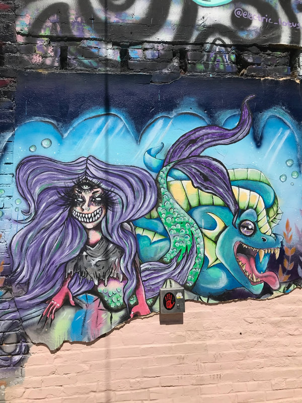 Street art in Boise's Freak Alley: stylized fierce mermaid and fish.